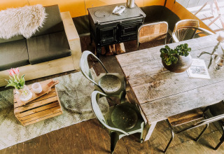 Cozy lodge interior with rustic dining table, wood stove, sofa, metal chairs, and decor at Beach Lodge Luxury.