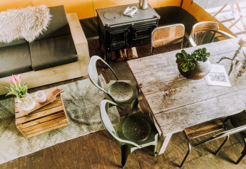 Cozy lodge interior with rustic dining table, wood stove, sofa, metal chairs, and decor at Beach Lodge Luxury.