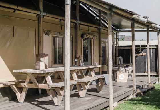 Außenterrasse mit Holzbänken am Beach Lodge Luxury im Duynpark Het Zwanenwater, Niederlande, sonnig.