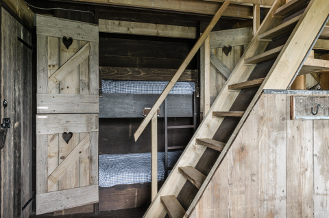 Rustic cabin interior with wooden bunk beds and staircase, Beach Lodge Luxury at Duynpark Het Zwanenwater.
