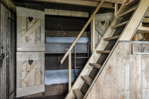 Rustikales Holzhütteninterieur mit Etagenbetten und Treppe, Beach Lodge Luxury im Duynpark Het Zwanenwater.