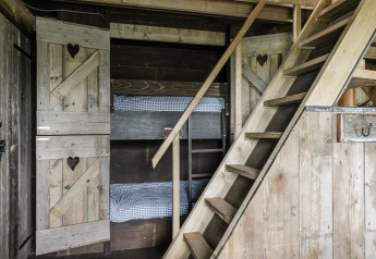 Rustic cabin interior with wooden bunk beds and staircase, Beach Lodge Luxury at Duynpark Het Zwanenwater.