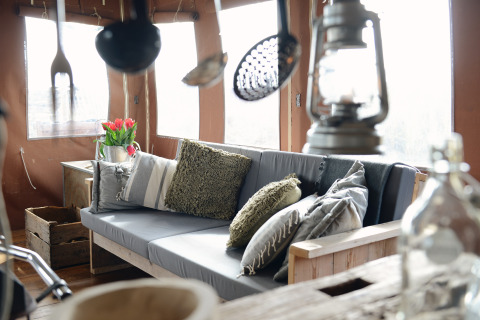 Gezellig lodge-interieur met sofa, kussens, lantaarn en bloemen bij Duynlodge in Duynpark Het Zwanenwater.