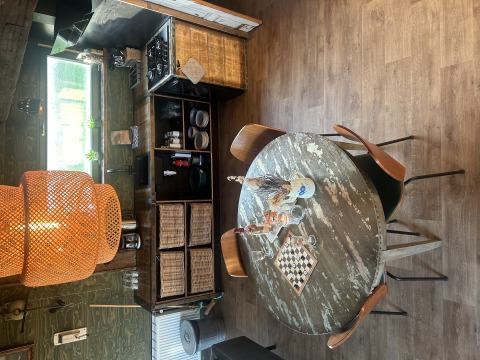 Rustiek lodge-interieur in Juttershut, Duynpark Het Zwanenwater, Nederland, met ronde tafel en mandenopslag.