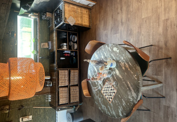 Interni rustici di lodge a Juttershut, Duynpark Het Zwanenwater, Paesi Bassi, con tavolo rotondo e cestini.