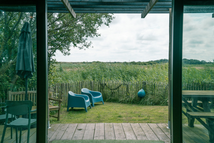 Blick von der Juttershut-Lodge im Duynpark Het Zwanenwater, Niederlande, mit Stühlen und grüner Wiese draußen.