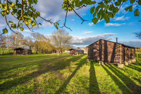 Solrig udsigt over feriepark Feather Down L'Étable des Mauges en Anjou med telthytter og grønt græs.