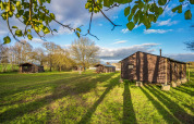 Sunny view of Feather Down L'Étable des Mauges en Anjou holiday park with tent lodges and grassy field.