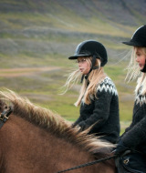 Dos niños con jerséis islandeses y cascos montan a caballo en el paisaje rural cerca de Beaupréau-en-Mauges.