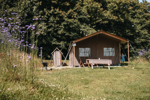 Campingplads ved Feather Down Ô manoir de Glams i Normandiet, med telt, legeredskaber og blomstereng.