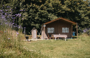 Campingplads ved Feather Down Ô manoir de Glams i Normandiet, med telt, legeredskaber og blomstereng.