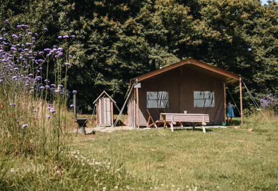 Campingplads ved Feather Down Ô manoir de Glams i Normandiet, med telt, legeredskaber og blomstereng.