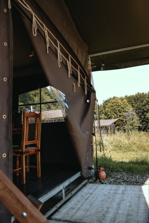 Vue depuis une tente au Feather Down Ô manoir de Glams, avec chaise en bois et nature, en Normandie.