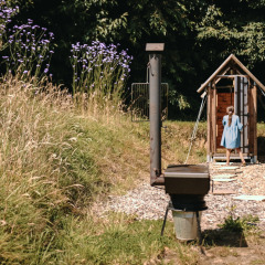 Una niña con vestido azul entra a una cabaña de madera en Feather Down Ô manoir de Glams en Normandía, Francia.
