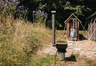 Una niña con vestido azul entra a una cabaña de madera en Feather Down Ô manoir de Glams en Normandía, Francia.