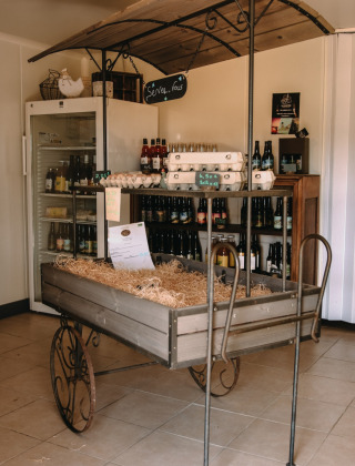 Un rincón rústico de tienda en Feather Down Ô manoir de Glams con huevos, bebidas y productos locales.