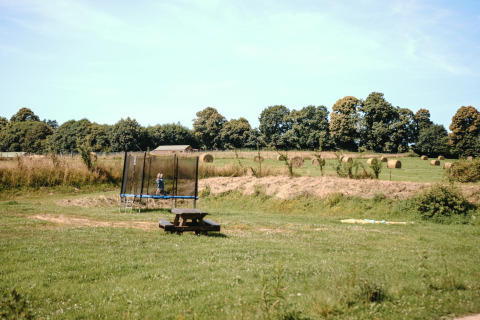En trampolin, et picnicbord og høballer på en grøn mark ved Feather Down Ô manoir de Glams i Normandiet.