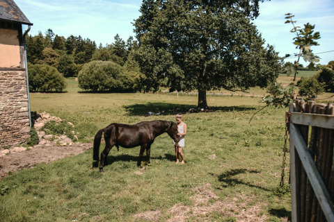 Ein Kind steht bei einem schwarzen Pony auf einer Wiese im Feather Down Ô manoir de Glams in der Normandie.