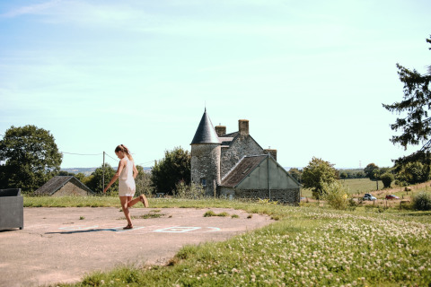 Woman plays outside at Feather Down Ô manoir de Glams holiday park in scenic Normandy countryside, France.