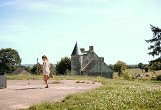 Frau spielt draußen bei Feather Down Ô manoir de Glams Ferienpark im malerischen Normandie, Frankreich.