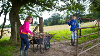 To børn samler grene ved en markport på BoerenBed Sunninglye Farm feriepark i Østengland.