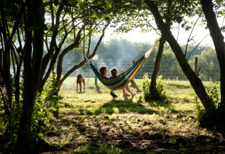 Dos personas descansan en una hamaca entre árboles en BoerenBed Sunninglye Farm, este de Inglaterra.
