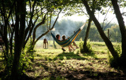 Two people relaxing in a hammock between trees at BoerenBed Sunninglye Farm in East of England.