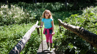 Pige på bro i grøn natur, BoerenBed Sunninglye Farm, feriepark i Østengland, Storbritannien.