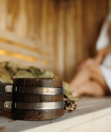 Intérieur d’un sauna dans un parc de vacances avec glamping, femme détendue avec serviette et louche.