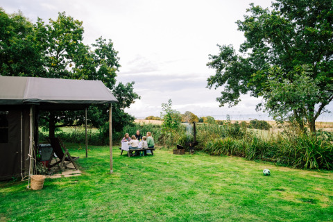 Familie genießt ein Picknick im Grünen am Feather Down Lunsford Farm Ferienpark in Südostengland, Großbritannien.