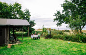 En familie sidder ved et picnicbord i det grønne græs ved Feather Down Lunsford Farm feriepark i Sydøstengland.