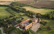 Luftfoto af Feather Down Layer Marney Tower feriepark i det østlige England, omgivet af grønne marker.