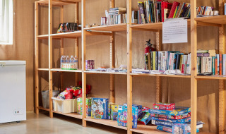 Étagères en bois avec livres, jeux de société et en-cas à Feather Down Layer Marney Tower, Angleterre.