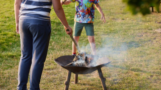 Des enfants s'occupent d'un brasero sur l'herbe au Feather Down Layer Marney Tower parc de vacances, Angleterre.