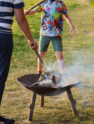 Des enfants s'occupent d'un brasero sur l'herbe au Feather Down Layer Marney Tower parc de vacances, Angleterre.