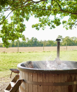 Bain nordique en bois extérieur sous des arbres à Feather Down Layer Marney Tower dans l’est de l’Angleterre.
