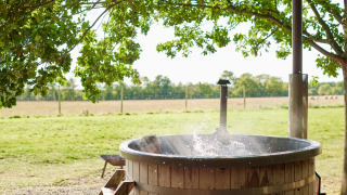 Bain nordique en bois extérieur sous des arbres à Feather Down Layer Marney Tower dans l’est de l’Angleterre.