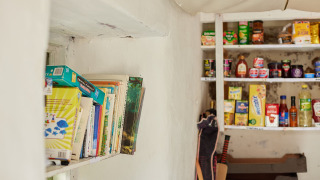 Estantería con libros y despensa con alimentos y juegos de mesa en Feather Down Pant y March Farm, Gales.