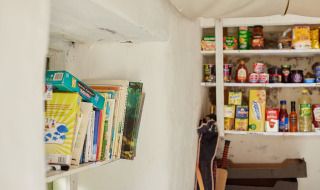 Bogreol og spisekammer på Feather Down Pant y March Farm, Wales, med madvarer og brætspil på hylderne.