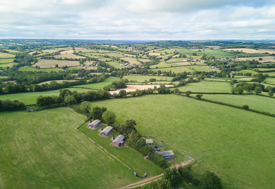 Luchtbeeld van Feather Down Billingsmoor Farm, een vakantiepark in Zuidwest-Engeland omringd door groene velden.