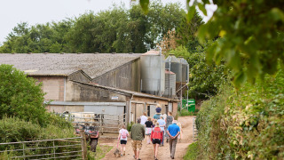 Familias pasean por un sendero rural en Feather Down Billingsmoor Farm en el suroeste de Inglaterra, Reino Unido.
