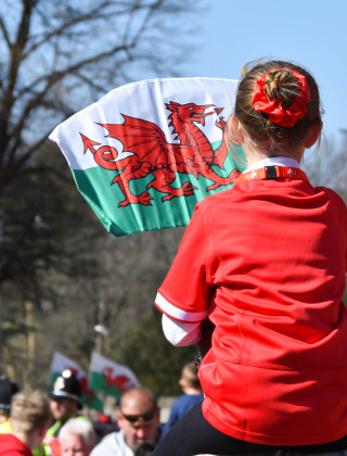 Una niña con camiseta roja ondea una bandera de Gales en una reunión al aire libre en Gloucester, Reino Unido.