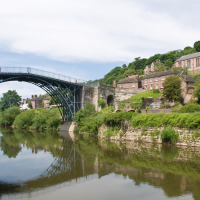 Puente de hierro histórico sobre un río junto a una iglesia y casas antiguas cerca de Gloucester, Inglaterra.