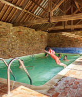 Piscina cubierta en Feather Down Moor Farm, Reino Unido, con niños y adultos disfrutando en ambiente rústico.