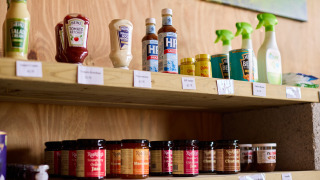 Estante con condimentos, salsas y productos de limpieza en Feather Down Treganhoe Farm, parque vacacional en Inglaterra.