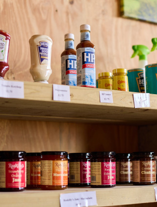 Hyldehylde med krydderier, saucer og rengøringsmidler på Feather Down Treganhoe Farm feriepark i England.
