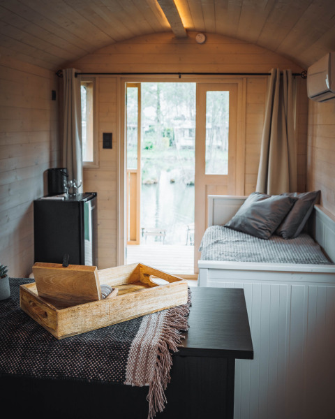 Interior del Gipsy wagon con terraza en Camping Papillon, Bélgica, diseño acogedor y ventanales grandes.
