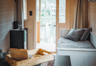 Interior del Gipsy wagon con terraza en Camping Papillon, Bélgica, diseño acogedor y ventanales grandes.