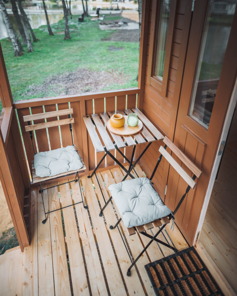 Pequeña terraza en la cabaña Gipsy wagon con dos sillas, mesa y vista al césped exterior.