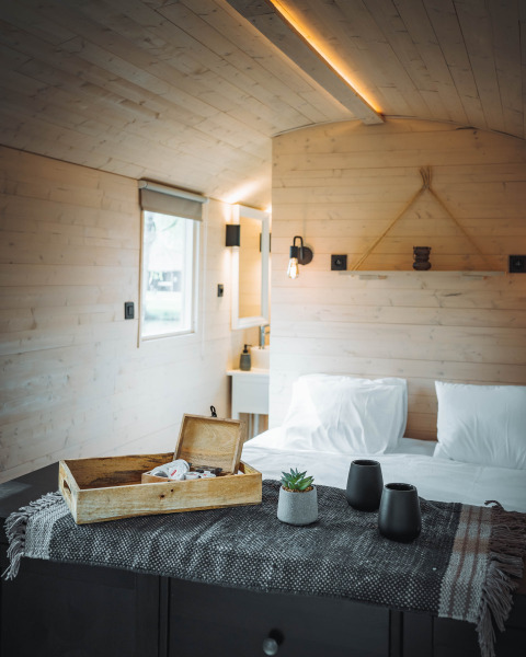 Cozy interior of Gipsy wagon cabin with wood walls, bed, and decor at Camping Papillon, Belgium.